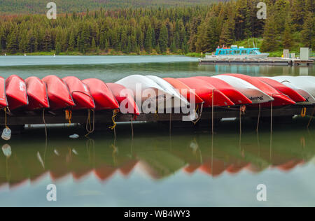 Red canoe sono impilati sul dock presso il Lago Maligne, Jasper National Park, Alberta, Canada. Foto Stock