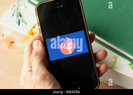 Mano che tiene uno smartphone con Facebook tinder dating icona sulla schermata. IPhone con un social media app logo. Amsterdam 2019.03.20 Foto Stock