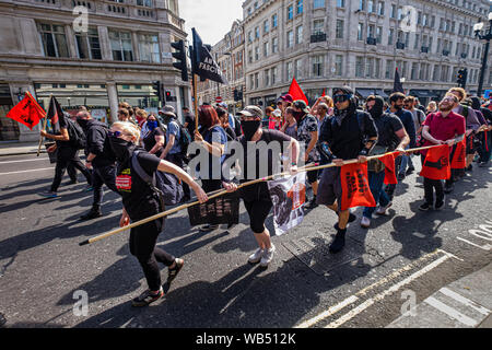 Londra, Regno Unito. 24 agosto 2019. Anti-fascisti marzo per opporsi a una protesta presso la BBC da Tommy Robinson sostenitori che affermano che egli è in carcere per il giornalismo. Egli è stato condannato a 9 mesi per 3 reati al di fuori di Leeds Crown Court che potrebbe aver causato il crollo di una toelettatura pista di prova e ha precedenti condanne per violenza, finanziari e frodi in materia di immigrazione, del possesso di droga e di ordine pubblico reati. La polizia ha mantenuto la due gruppi separati. Robinson sostenitori sono stati successivamente unite dai dimostranti da Trafalgar Square, e un gruppo di grandi dimensioni dal supporto fino al razzismo è venuto per unire Antifa. Peter Marshall / Alamy Live Foto Stock