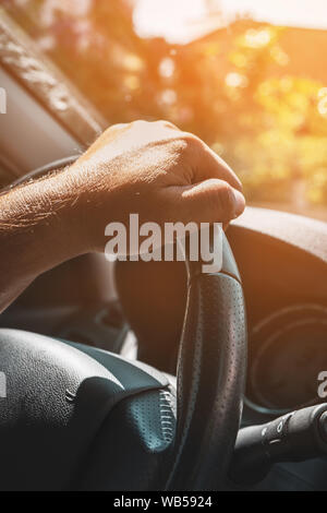 Immagine ravvicinata di un uomo con le mani in mano tenendo un auto del volante. Foto Stock