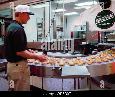 Orologi dipendente dalla linea di produzione presso la nazione prima Krispy Kreme donut shop in Winston-Salem, Carolina del Nord Foto Stock