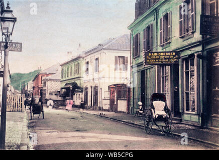 [ 1890 Giappone - Main Street a Yokohama ] - Negozi in Honcho-dori a Yokohama, nella prefettura di Kanagawa. Il fotografo si fermò vicino a n. 60 dove Maebashi-cho interseca con Honcho-dori. Lanterne a gas la linea street. Sulla destra un rickshaw è parcheggiato di fronte alla creazione di proprietà di T. laurea, che curiosamente è un parrucchiere, un sigaro importatore e rivenditore in francobolli. Xix secolo albume vintage fotografia. Foto Stock