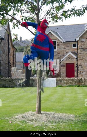 Rennington, Inghilterra, 24 agosto 2019. Spiderman la filatura di un web in un albero durante lo spaventapasseri festival che si tiene ogni anno a Ferragosto weekend. Foto Stock