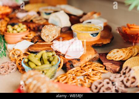 Colpo selettivo di senape, salsicce a fette, cetrioli sottaceto e biscotti su tavola di legno Foto Stock