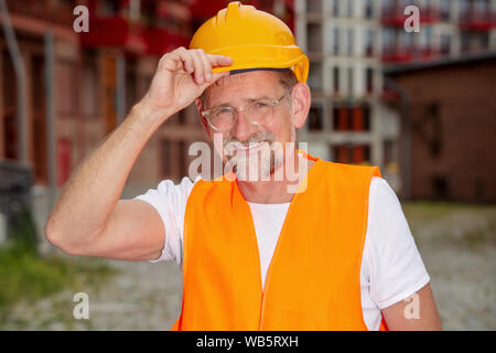 Ritratto di bello il lavoratore nel suo 50s con casco in piedi al di fuori Foto Stock