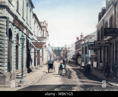 [ 1890 Giappone - Main Street a Yokohama ] - Un uomo tira un rickshaw davanti ai negozi in Honcho-dori a Yokohama, nella prefettura di Kanagawa. Il fotografo si fermò vicino a n. 60 dove Maebashi-cho interseca con Honcho-dori. Lanterne a gas la linea street. Xix secolo albume vintage fotografia. Foto Stock