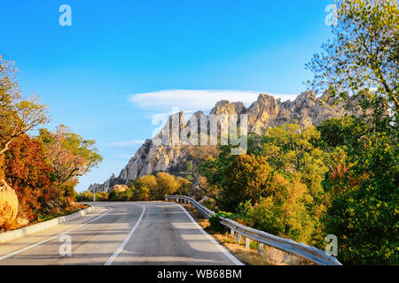 Strada vuota senza automobili, in Sardegna in Italia in estate. Panorama con autostrada e il verde della natura e il blu del cielo. Le montagne sullo sfondo. Foto Stock