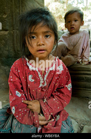 Due bambini di strada seduti nell'antico tempio Khmer di Ta Prohm nella regione di Angkor vicino a Siem Reap, Cambogia. Foto Stock