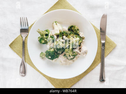 Broccoli cotti al forno con pollo su una piastra bianca. Vista superiore, close-up. Una sana e corretta alimentazione. Foto Stock