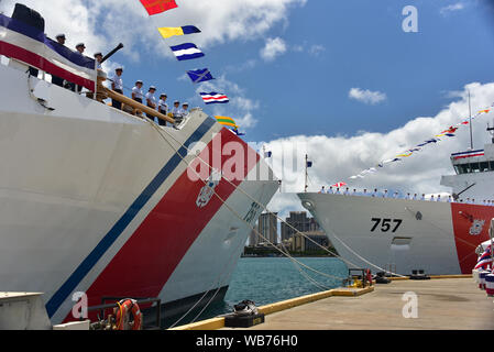 Il suo equipaggio da Guardacoste Kimball WMSL (756), il primo piano e Guardacoste Midgett WMSL (757) linea le rotaie per "portare le navi a vita" durante una doppia unica cerimonia di messa in servizio per i coltelli di taglio in corrispondenza della Guardia Costiera Honolulu Base 24 agosto 2019. Le navi sono la settima e ottava posizione legenda classe di sicurezza nazionale taglierine commissionata dalla Guardia Costiera e le prime due homeported nelle Hawaii. (U.S. Coast Guard foto di Chief Petty Officer John Masson/rilasciato) Foto Stock