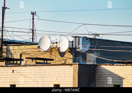 Antenne paraboliche sul tetto dell'edificio contro il cielo blu. Tecnologia. Foto Stock