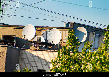 Antenne paraboliche sul tetto dell'edificio contro il cielo blu. Tecnologia. Foto Stock