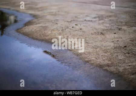 Strada concreta e l'acqua di allagamento. prosciugamento povero sistema pozza di sinistra di inondare la tempesta di pioggia di acqua sulla superficie della strada Foto Stock