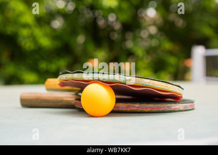 Ping pong pale e la sfera sul retro blu sullo sfondo di legno. Racchette rovinato dal tempo Foto Stock