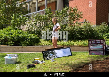 Storrs, CT, Stati Uniti d'America. Aug 2019. Lone coed femmina con forniture in tutto il prato prendendo una pausa dal muoversi al suo nuovo dormitorio. Foto Stock