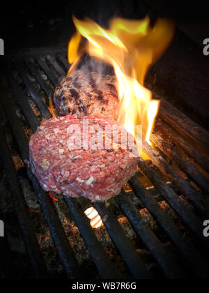 Hamburger fatti in casa o tortino la cottura su una griglia di fiamma Foto Stock