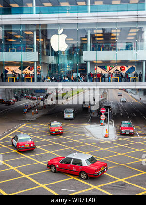 Red taxi passando dagli Apple Store in centrale. Hong Kong, Cina. Foto Stock