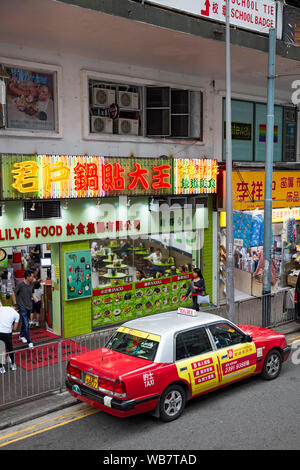 Red taxi sulla strada nel quartiere centrale. Hong Kong, Cina. Foto Stock