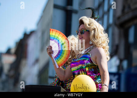 Un esecutore da Minsky's show bar con un arcobaleno ventola durante l'Orgoglio Cymru 2019 parade di Cardiff. Foto Stock