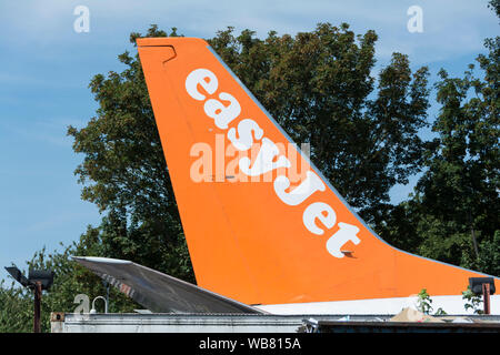 Close-up di un piano easyJet pinna di coda al di fuori del easyFood e easyBus store sulla North Circular Road, London, NW10, Regno Unito Foto Stock