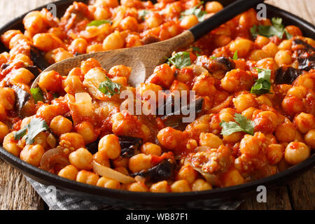 Piatto di stufati di ceci con melanzane, pomodori, cipolle, erbe aromatiche e spezie close-up su una piastra sul tavolo orizzontale. Foto Stock