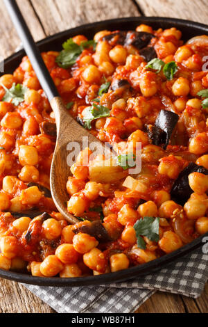 Israeliano cucina vegetariana stufato di ceci con melanzane, pomodori, cipolle e spezie closeup su una piastra sul piano verticale. Foto Stock