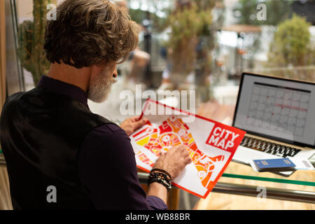 L'uomo ad esplorare la mappa della città prima di andare a fare una passeggiata. Foto Stock