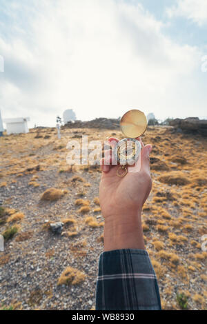 Donna di mano che tiene una bussola con una montagna in background Foto Stock