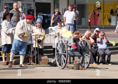 Gloucester, Gloucestershire, UK. 25 Ago, 2019. La guerra civile ri Enactors trapano e fire moschetti in King Square Gloucester City Centre. Appassionati a riportare in vita i luoghi e i suoni del xvii secolo assedio di Gloucester. Lo sparo del cannone. Credito: Signor Standfast/Alamy Live News Foto Stock