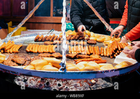 Barbecue tradizionale barbecue wurst salsicce sul mercato di Natale in Germania in Europa in inverno. Il tedesco strada notte Xmas e fiera vacanze in città europea Foto Stock