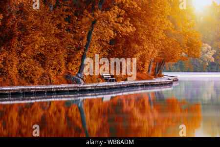 Passerella in legno intorno al lago di Bled con le montagne e le case sullo sfondo. Paesaggio autunnale. Bellissima natura slovena in autunno. Bled, sloveni Foto Stock