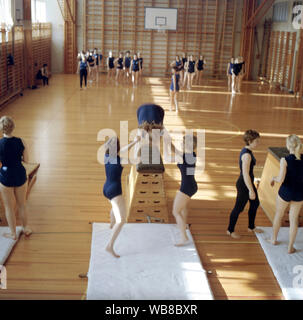 Scuola ginnastica negli anni sessanta. Un insegnante in una scuola palestra si tiene una lezione e gli studenti sono in ascolto alle sue istruzioni. La Svezia degli anni sessanta Foto Stock