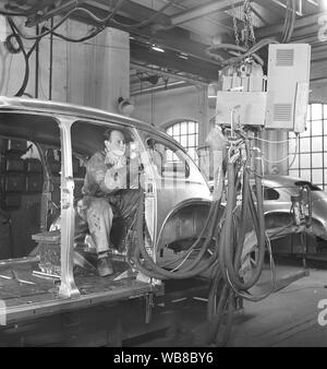 Produzione di automobili nel 1940s. Un lavoratore in una vettura linea di assemblaggio utilizzare un attrezzo idraulico per il montaggio di parti della vettura insieme. Dopo la II guerra mondiale diverse aziende in Svezia ricevuto le vetture in parti e li assembeled. Era un costo inferiore per l'importazione di parti di automobili quindi tutta la vettura. La Svezia 1948. Kristoffersson ref AP89-4 Foto Stock