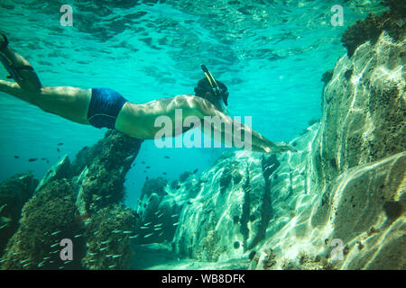 Uomo bello divertirsi in vacanza estiva ed esplorare il fondale durante le immersioni subacquee in mare. Foto Stock