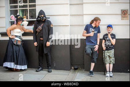 Due steampunks sono nella foto accanto a un padre e figlio a mangiare il gelato durante l'Asilo Steampunk Festival, a Lincoln, il più grande e più lunga di steampunk festival in tutto il mondo. Picture Data: domenica 25 agosto, 2019. Quattro giorni di festival, asilo Steampunk Festival, attira i partecipanti provenienti da tutto il mondo come le strade di Lincoln sono assediati con migliaia di steampunks godendo di un festival che si propone di coniugare arte, letteratura, musica, moda e della commedia. Foto di credito dovrebbe leggere: Danny Lawson/PA FILO Foto Stock