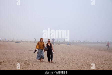 Portobello Beach, Edimburgo, Scozia, Regno Unito. 25 Ago, 2019. La haar o mare fret come è noto in termini di meteorologia è un mare freddo nebbia in laminato sul Firth of Forth due primi femmina gente sulla spiaggia a piedi lungo la sabbia come il 16 grado di temperatura li ha attratti verso la costa. Foto Stock