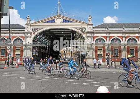 I ciclisti gruppo ciclismo equitazione biciclette in strada al di fuori della parte anteriore del mercato Smithfield edificio nella città di Londra EC1 Inghilterra UK KATHY DEWITT Foto Stock