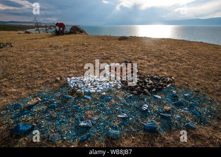 Sulla terra, pietre sono previsti sotto forma di due cigni e un cuore che si affaccia sul lago Baikal. Simbolo dell'amore. Nero e cigno bianco su un lago blu. Il Foto Stock