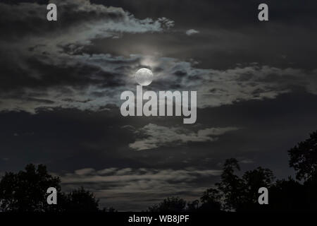 Luna piena parzialmente nascosto da nuvole Foto Stock