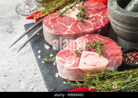 Freschi Stinco di vitello fette di carne di manzo per osso buco per la cottura sul tagliere con ingredienti e condimenti timo, pepe, sale. Foto Stock