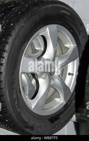 Un rack con un nuovo inverno chiodati semplice e gomma di pneumatici per auto. Su un disco di cast e metallo stampato. Close-up. Foto Stock