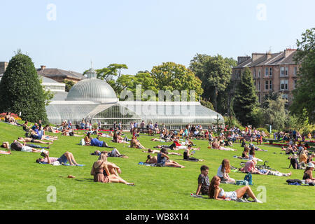 Glasgow, Scotland, Regno Unito. Il 25 agosto 2019. Come le temperature si elevano a oltre 26C in Glasgow dopo giorni di pioggia e vento freddo, popolo gregge alla città in spazi aperti di George Square e i Giardini Botanici di prendere vantaggio di fine estate il sole su questo a Ferragosto, per rabboccare il loro tans e rilassarsi. Credito: Findlay/Alamy Live News Foto Stock