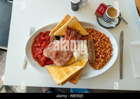 Primo piano di una colazione inglese completa su una piastra con caffè nero Foto Stock