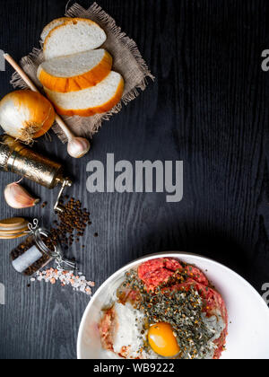 Di carne macinata con cipolla fresca, aglio, erbe su sfondo di legno Foto Stock