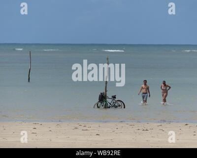 Un paio di passi indietro per salvare le loro biciclette dalla marea crescente su una spiaggia brasiliana Foto Stock