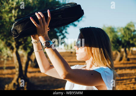 Giovane donna con una custodia per il notebook attraverso il campo di oliva Foto Stock