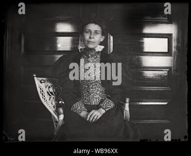 Ritratto di donna nella sedia di vimini che indossa. Inizio periodo edoardiano fotografia amatoriale, scandita dall'originale 3x4 pollici lastra di vetro negativo circa primi 1900s. Foto Stock