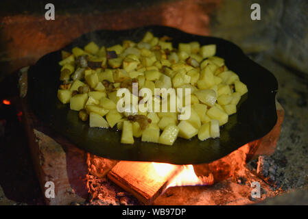 La cottura di patate arrosto per picnic Barbecue.barbecue fritte le patate in una padella larga su un fuoco aperto con fumo.Croccante cotta nel forno le patatine fritte al Foto Stock