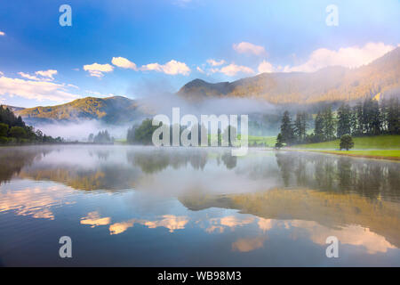 Mattina splendido paesaggio di montagna delle Alpi e del lago con riflessioni, foggy Foto Stock