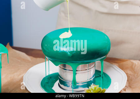 Mousse di torta di yogurt. Ragazze cook e creano un disegno di mousse sulla torta. Specchio congelati ciliegina sulla torta. Capolavori culinari Foto Stock